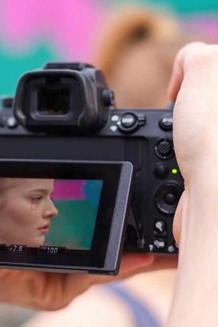 Photographer taking shot of a young blonde woman in sportswear at outdoors training, multicolored background